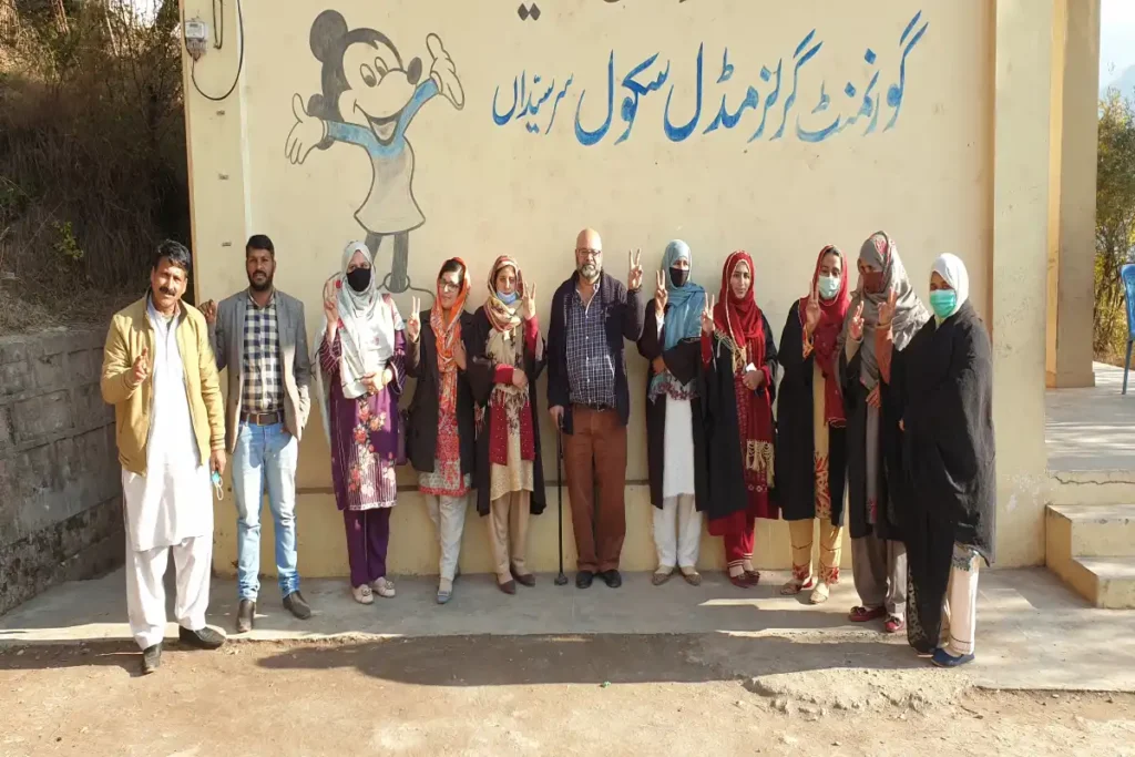 Group of successful teachers celebrating outside a school, symbolizing the achievement of QTS requirements.